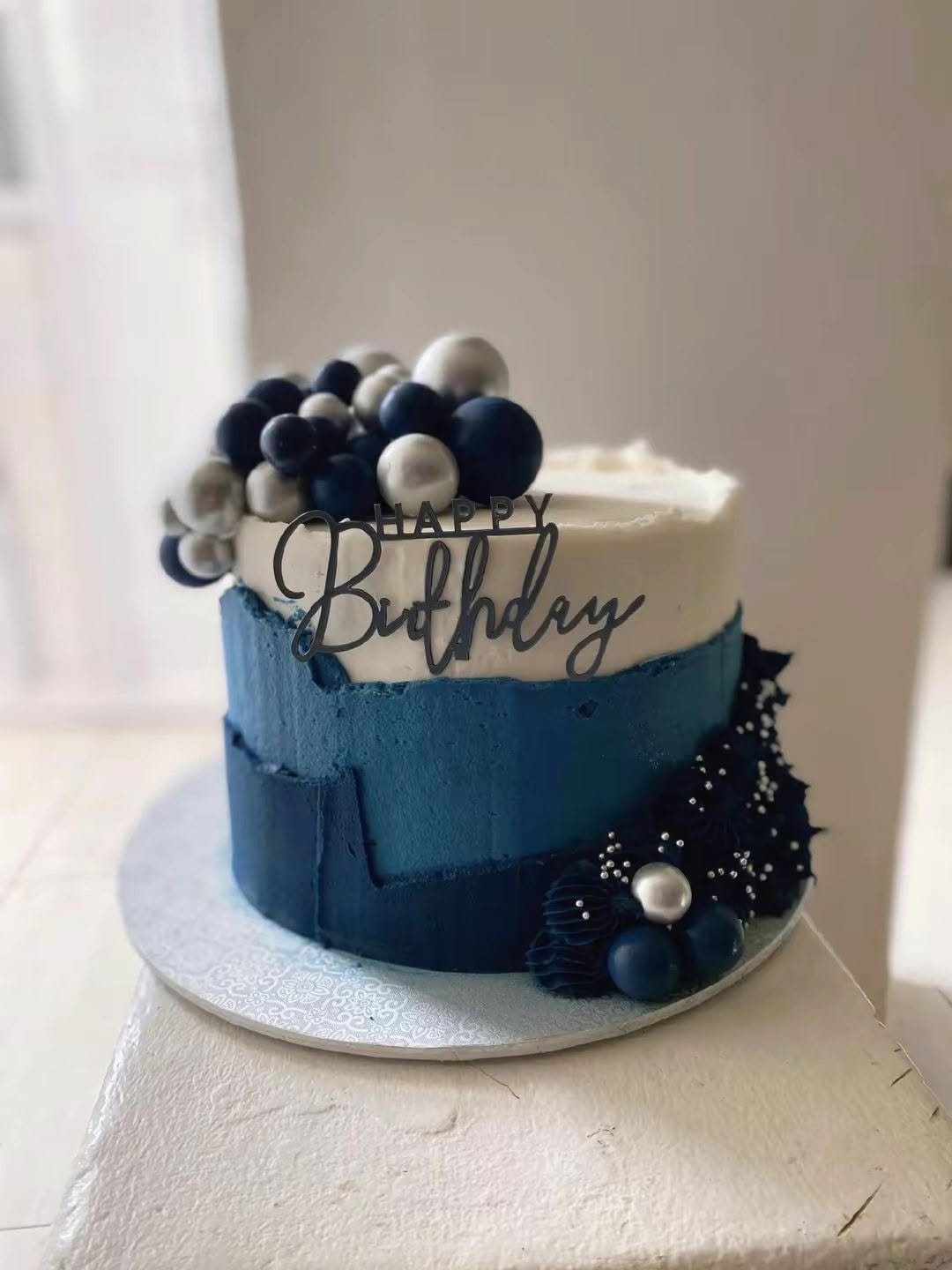 Navy and white birthday cake with decorative topper